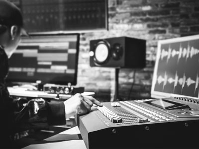 asian male professional sound engineer working in digital recording, broadcasting, editing studio. focus on mixer fader