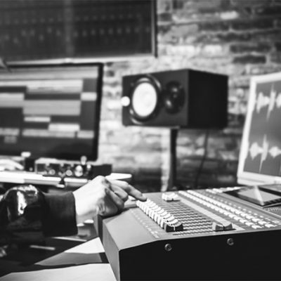 asian male professional sound engineer working in digital recording, broadcasting, editing studio. focus on mixer fader